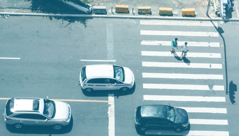 coches circulando por la carretera y peatones cruzando